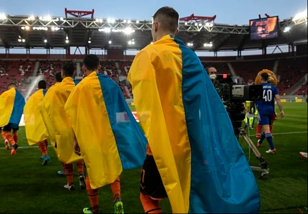 Jogadores vão ao gramado do estádio exibindo a bandeira da Ucrânia