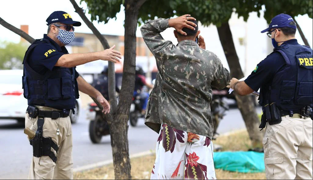 Policiais tranquilizando irmão da vítima 